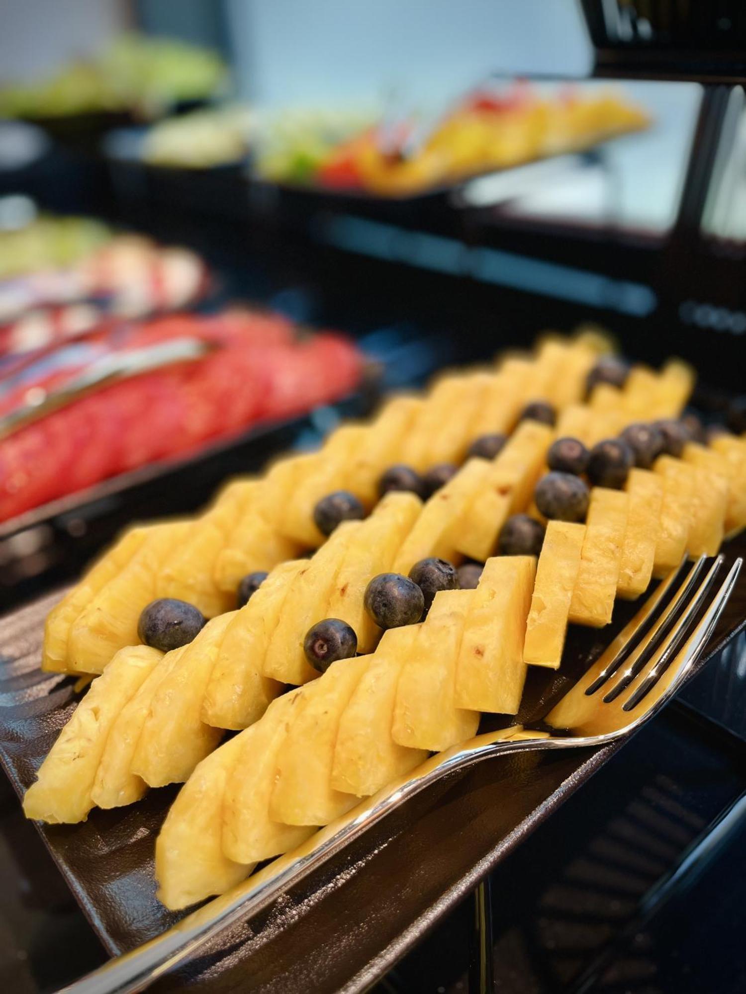 Royal Tulip Warsaw Centre Aparthotel Ngoại thất bức ảnh The photo shows a colorful fruit display featuring neatly arranged slices of yellow pineapple, interspersed with dark blueberries. The pineapple slices are cut into a checkerboard pattern, creating an appealing presentation. In the background, other 